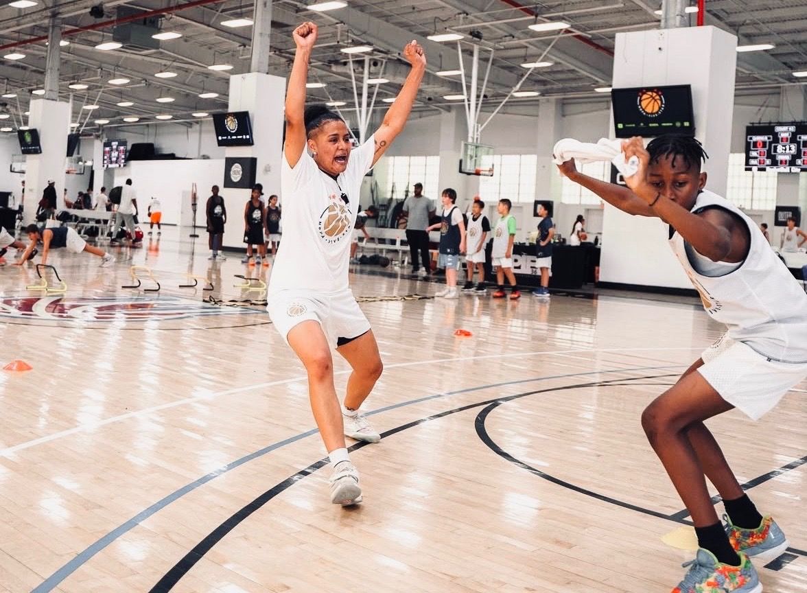 Coach Nay celebrating with a young player at a basketball camp